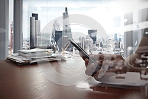 Double exposure of businessman hand use smart phone with office