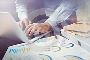 Double exposure of businessman hand working laptop on wooden desk in office in morning light. The concept of modern work