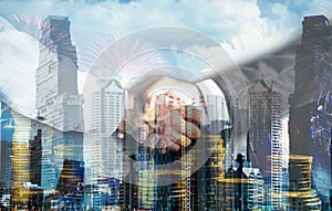 Double Exposure of a businessman handshake on the city building background