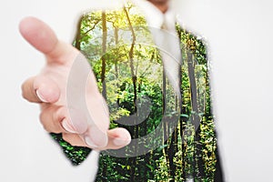 Double exposure, Businessman stretching hand to hand shake with Green trees in the forest. Eco friendly and sustainable business