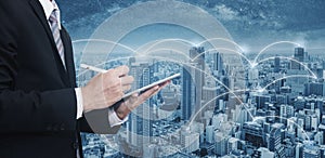 Double exposure businessman using digital tablet, and cityscape. Business network, blockchain technology and internet connection