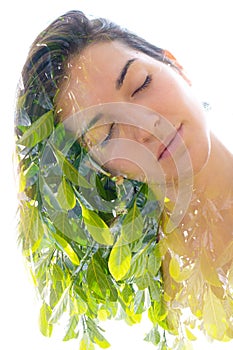 Double exposure close up portrait of a young pretty woman interwoven with bright leaves of a vibrant tropical tree