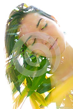 Double exposure close up portrait of a young pretty woman interwoven with bright leaves of a vibrant tropical tree