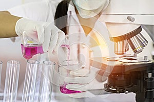 Scientist woman research carrying chemistry liquid with microscope equipment for research experiments to test tube