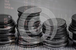 Double exposure of coin stack with stock market screen chart boa