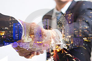 Double exposure concept. Investor business handshake with city night. Businessman shaking hands photo