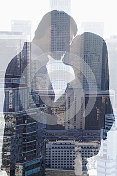 Double exposure of couple kissing over cityscape, side view, silhouette