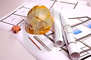 Double exposure of crude oil pumps and hard hat on table with construction drawings