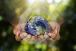 Double exposure of hands holding planet earth on blurred green nature background, elements of this image furnished
