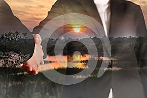 Double exposure of handshake and sunrise on the cornfield