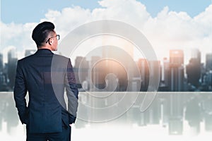 The double exposure image of the business man standing back during sunrise overlay with cityscape image. The concept of modern lif