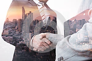 The double exposure image of the businessman handshaking with another one during sunrise overlay with cityscape image.