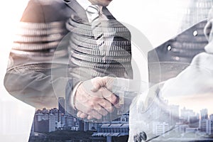 The double exposure image of the businessman handshaking with another one during sunrise overlay with coin stack image.