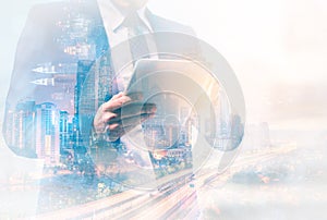 Double exposure image of businessman using digital tablet on city blurred background. Business success concept