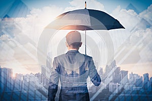 The double exposure image of the Businessmen are spreading umbrella during sunrise overlay with cityscape image. The concept of mo