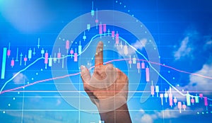Double exposure of man`s hand touch to blue sky and graph of stock market on laptop screen , Trading on stock market and financia