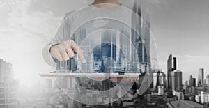 Double exposure, a man using digital tablet, and modern buildings hologram. Real estate business and building technology concept