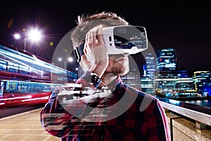 Double exposure, man wearing virtual reality goggles, night city