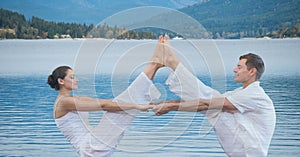 Double exposure of man and woman performing yoga exercising over lake