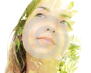 A double exposure portrait of a dreamy young woman looking away from the camera combined with a photo of green leaves