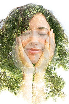 A double exposure portrait of a half smiling young woman with eyes closed holding her chin with hands and a tree