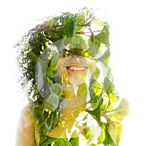 A double exposure portrait of a young woman combined with green foliage