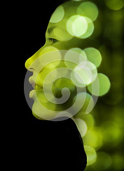 A double exposure portrait of a young woman's profile against black background