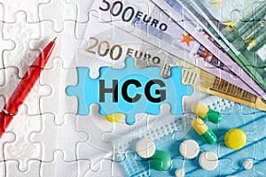 Double exposure. Puzzles with the image of pills, medical mask, pens and euro with the inscription -HCG