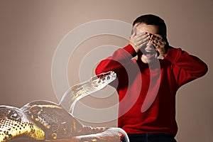 Double exposure of scared boy suffering from herpetophobia on beige background. Fear or aversion to reptiles