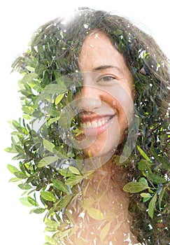 A double exposure of a smiling young woman`s portrait and tree leaves