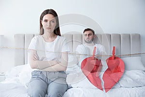 Double exposure with unhappy couple with relationship problems and halves of torn heart pinned on laundry string