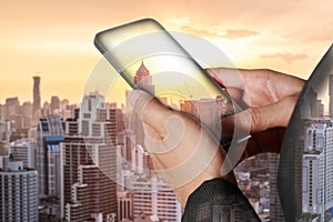 Double exposure of woman hand hold and touch screen smart phone, tablet,cellphone and sunrise cityscape