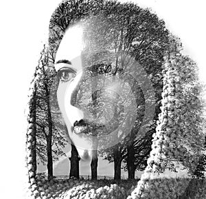 Double exposure of young beautiful girl among the leaves and trees. Portrait of attractive lady combined with photograph of tree.