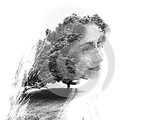 Double exposure of young beautiful girl among the leaves and trees. Portrait of attractive lady combined with photograph of tree.