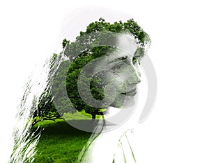 Double exposure of young beautiful girl among the leaves and trees. Portrait of attractive lady combined with photograph of tree.