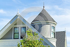 Double gable house roof with window and decorative ornament and home spire or turret on white house with gray roof