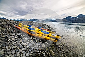 Double kayaks parked on the bay on scenic mountain ocean bay during arctic expedition.