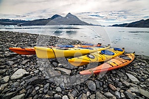 Double kayaks parked on the bay on scenic mountain ocean bay during arctic expedition.