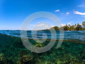 Double landscape with sea and sky. Split photo with tropical island and underwater coral reef.