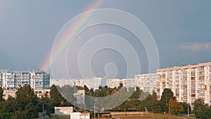 Double Multicolored Bright Rainbow in Sky above Roofs Modern Buildings in Town