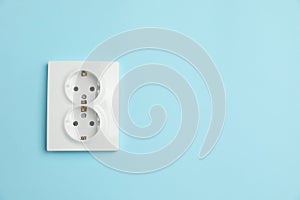 Double power socket on light blue wall, space for text. Electrical supply