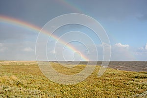 Double rainbow above flat coastal landscape