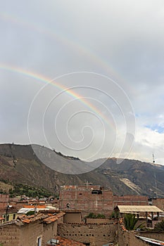 Double rainbow in the afternoon, with view of some adobe and brick houses, mountains and sky, taken in the afternoon in Caraz