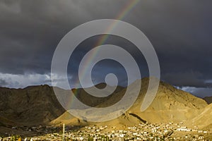 A double rainbow in the dark evening sky over the village in a mountain desert valley