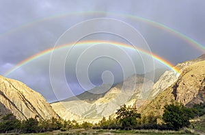 Double rainbow and heavy rain over the mountain valley