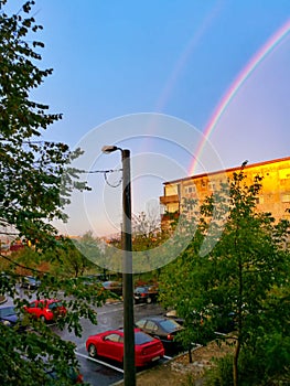 Double rainbow over block of flats and parking lot