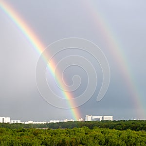 Double rainbow over forest and city in spring