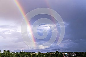 Double rainbow over the forest and houses