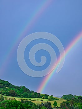 Double rainbow over the hill on the dark sky