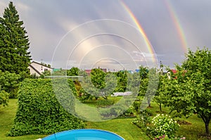 Double rainbow over houses and over the garden